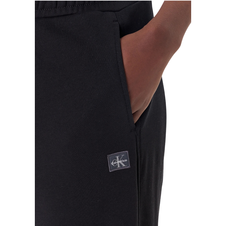 Detalle del bolsillo y logo de pantalón negro Calvin Klein Jeans en french terry