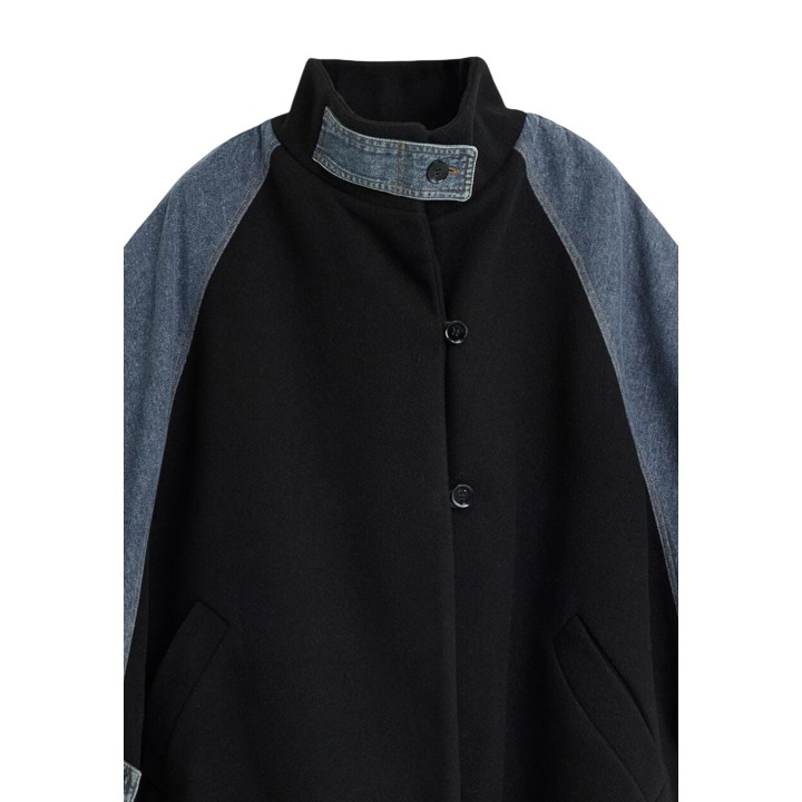 Detalle frontal del cuello y cierre de poncho Desigual negro con denim azul