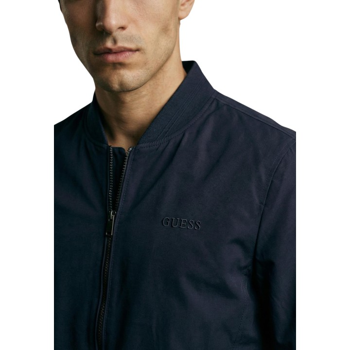 Detalle frontal de chaqueta bomber azul Guess para hombre con logo