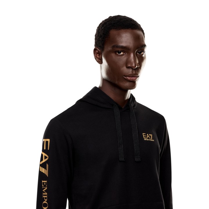 Detalle frontal de sudadera de hombre EA7 negra con capucha y logo dorado