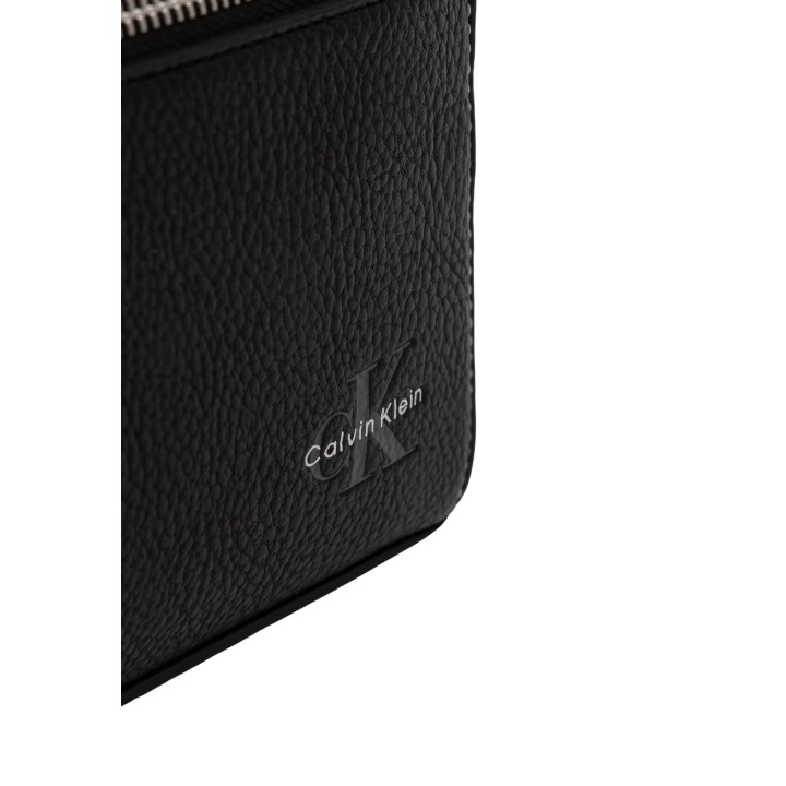 Detalle del logo Calvin Klein en bolso negro de piel granulada