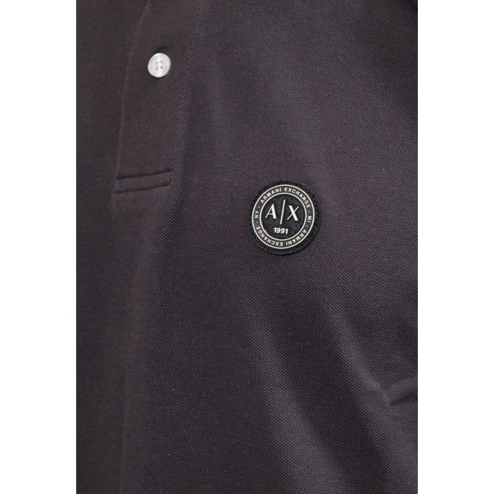 Detalle del logo Armani Exchange en polo negro de hombre
